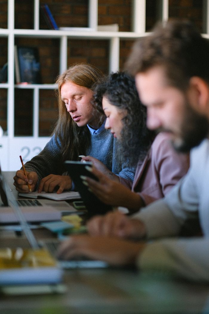 About Focused coworkers sitting at table and working on startup strategy in modern open space
